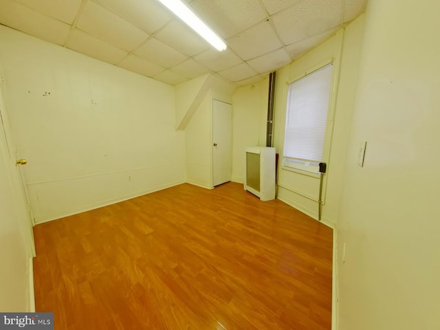 basement with a drop ceiling and hardwood / wood-style floors