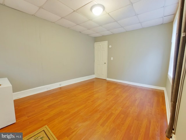 spare room with a drop ceiling and hardwood / wood-style flooring