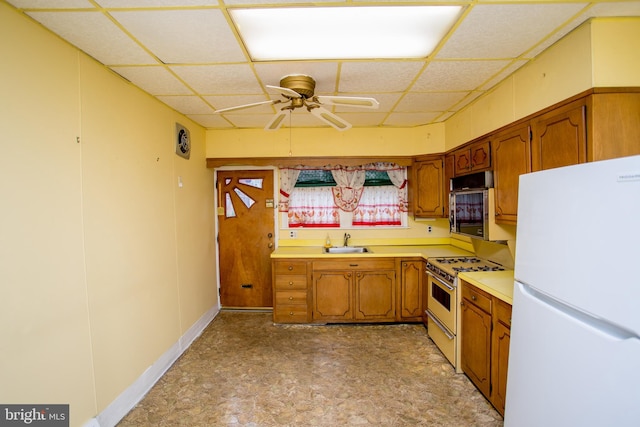 kitchen featuring ceiling fan, a drop ceiling, sink, and white appliances