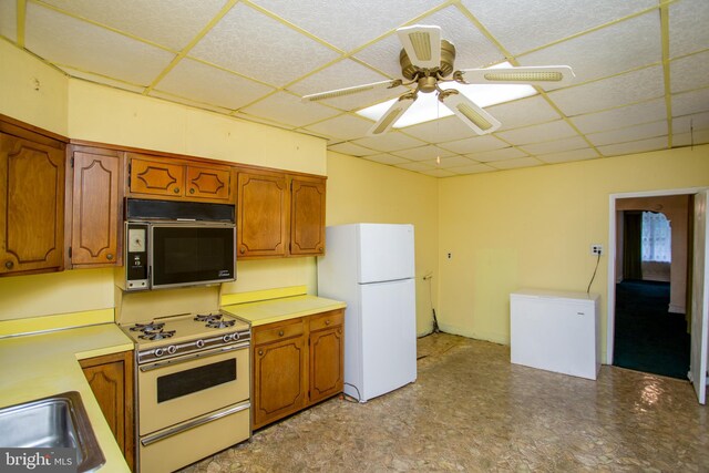 kitchen featuring a drop ceiling, white appliances, ceiling fan, and sink