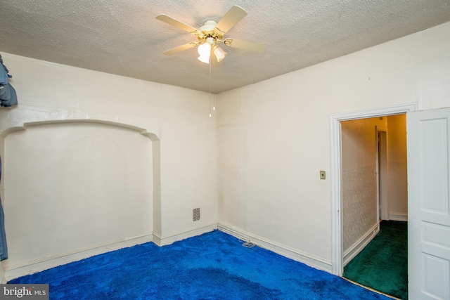 carpeted empty room with ceiling fan and a textured ceiling