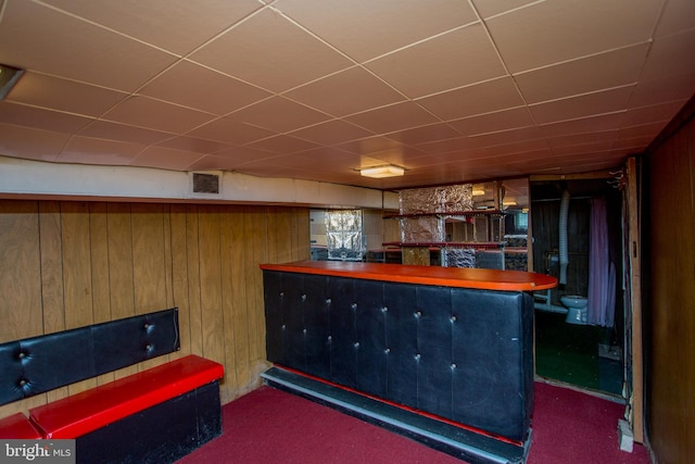 bar with dark colored carpet and wood walls