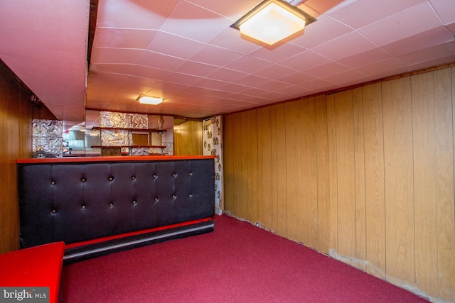 basement with carpet floors, bar area, and wood walls