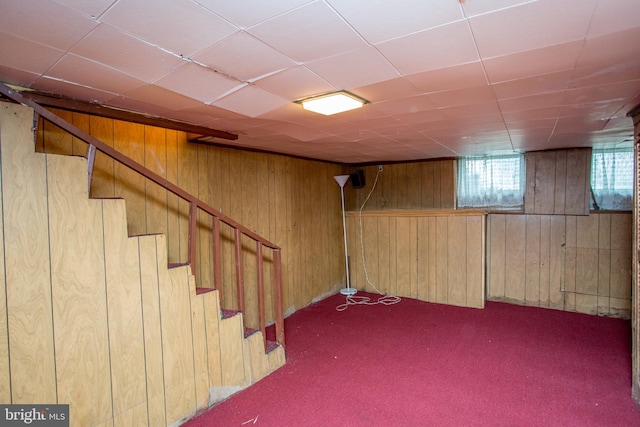 basement featuring wooden walls and dark colored carpet