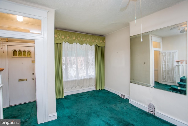 carpeted empty room featuring a textured ceiling and ceiling fan