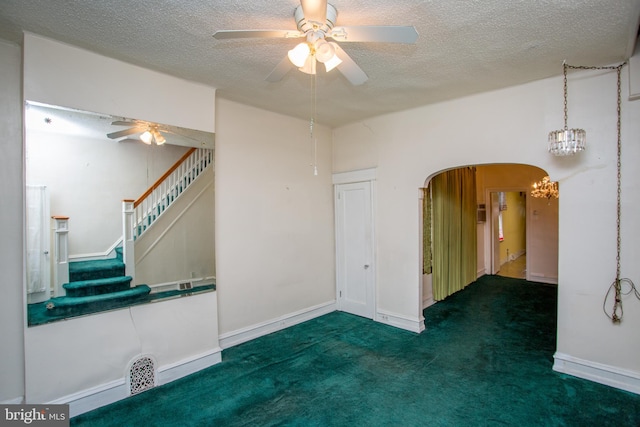 carpeted empty room with a textured ceiling and ceiling fan with notable chandelier