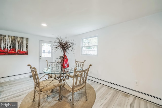 dining space with a baseboard radiator, light hardwood / wood-style flooring, and a wealth of natural light