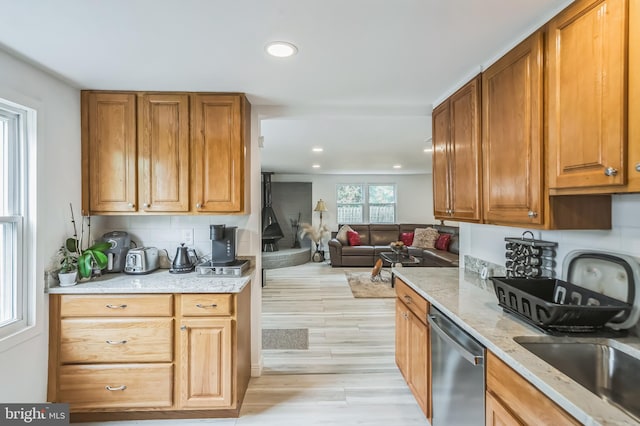 kitchen featuring light stone countertops, dishwasher, light hardwood / wood-style flooring, and backsplash