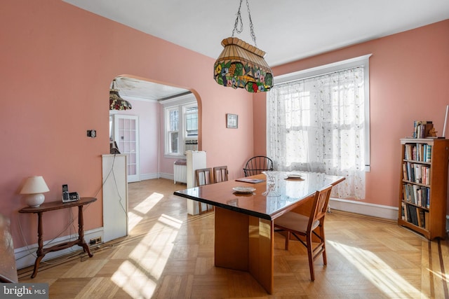 dining area with radiator heating unit, crown molding, and light parquet flooring