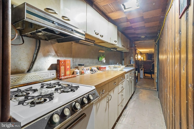 kitchen featuring ventilation hood, white cabinets, and white gas stove