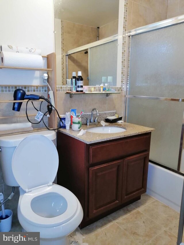 full bathroom with vanity, toilet, tasteful backsplash, tile patterned floors, and combined bath / shower with glass door