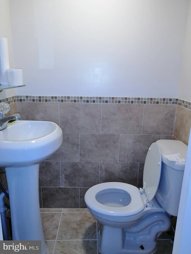 bathroom with tile walls and toilet