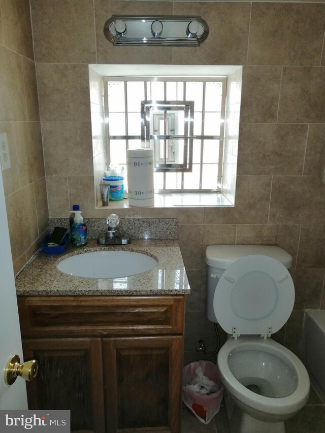 bathroom featuring tile walls, vanity, and toilet