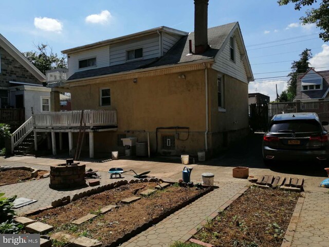 back of house with a fire pit, a deck, and a patio area