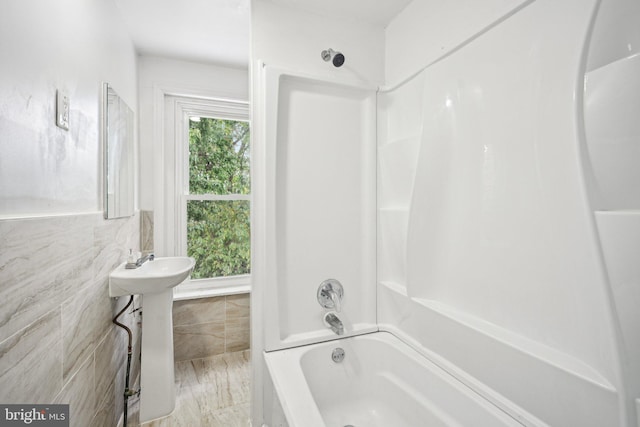 bathroom with tub / shower combination and tile walls