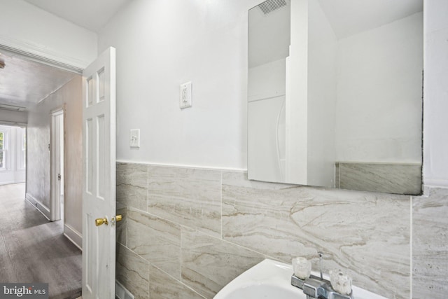 bathroom featuring hardwood / wood-style flooring, tile walls, and sink