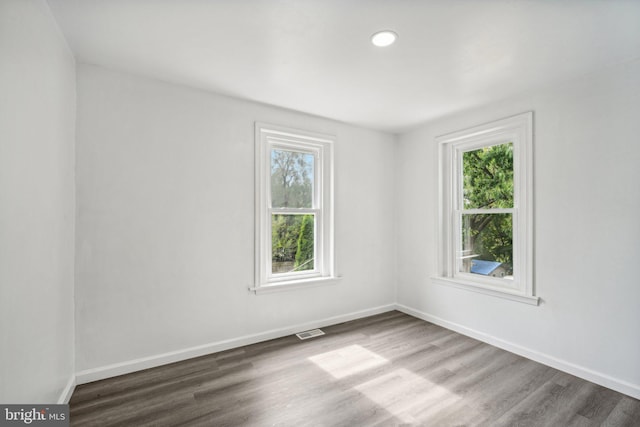 empty room with hardwood / wood-style flooring and a healthy amount of sunlight