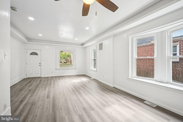 foyer featuring ceiling fan, ornamental molding, light wood-type flooring, and a tray ceiling