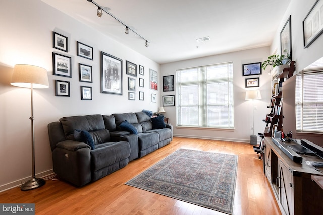 living room with light hardwood / wood-style floors and track lighting