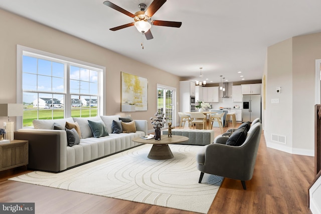 living room featuring light hardwood / wood-style flooring and ceiling fan with notable chandelier