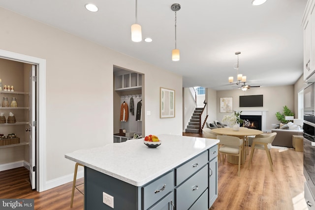 kitchen with white cabinets, a kitchen island, light hardwood / wood-style flooring, and decorative light fixtures