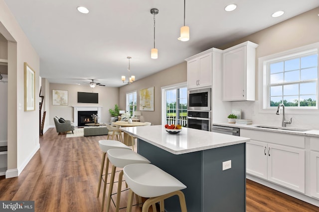 kitchen with a kitchen island, stainless steel appliances, decorative backsplash, a sink, and white cabinetry