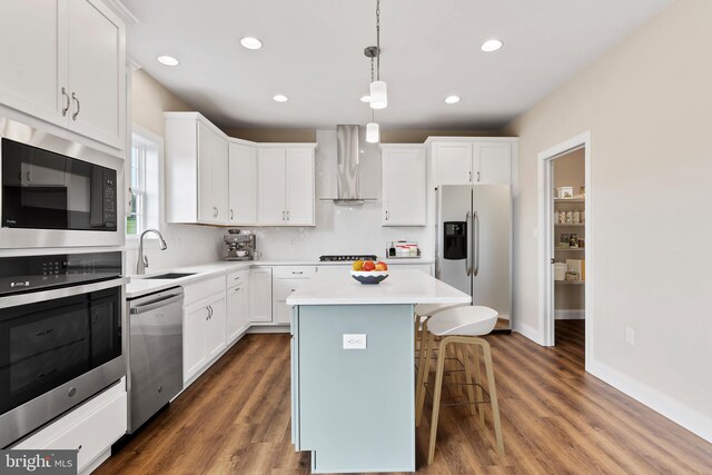 kitchen with white cabinetry, wall chimney exhaust hood, stainless steel appliances, a center island, and dark hardwood / wood-style floors