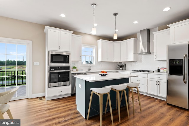 kitchen featuring a sink, backsplash, a center island, appliances with stainless steel finishes, and wall chimney exhaust hood