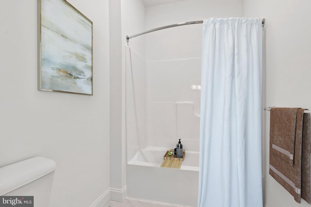 bathroom featuring baseboards, toilet, and shower / tub combo with curtain