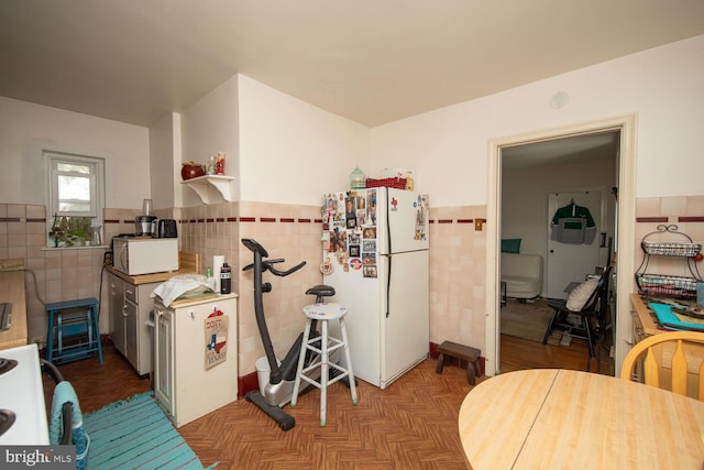 kitchen with tile walls, white appliances, and light parquet flooring