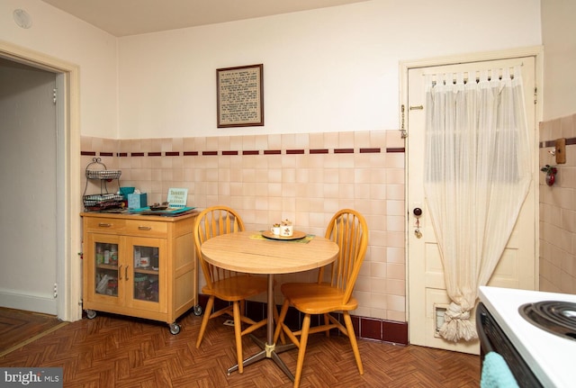 dining space featuring tile walls and dark parquet floors