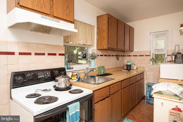 kitchen with decorative backsplash, dark parquet flooring, electric range, and sink