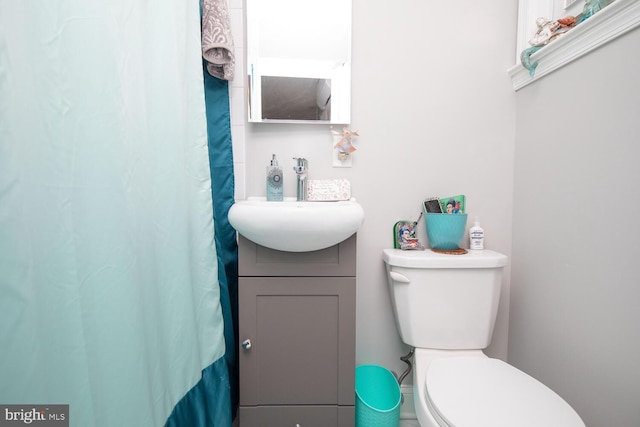 bathroom with curtained shower, vanity, and toilet