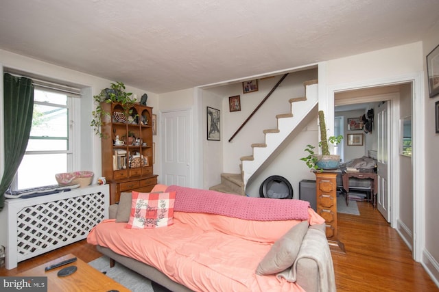 living room with a textured ceiling, light hardwood / wood-style floors, and radiator