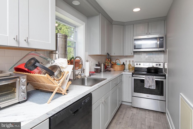 kitchen featuring appliances with stainless steel finishes, light wood-type flooring, sink, and decorative backsplash