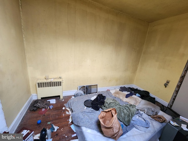 bedroom with radiator heating unit and dark hardwood / wood-style floors