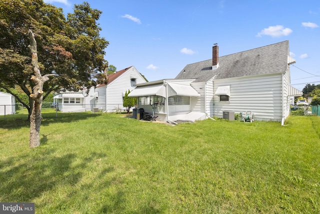 rear view of property featuring a lawn and central AC unit