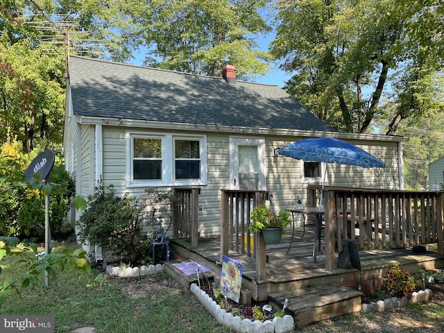 back of property featuring a deck, a shingled roof, and a chimney