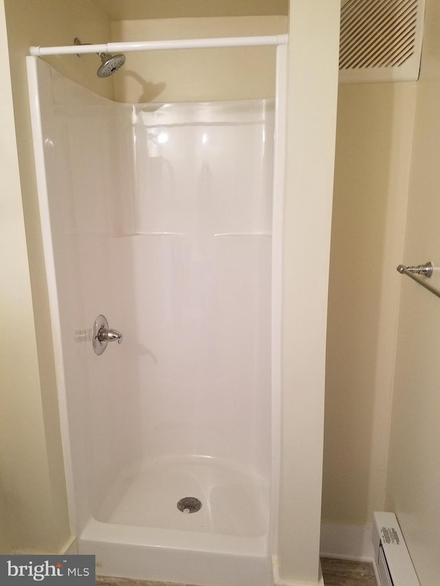 bathroom featuring a baseboard heating unit and a shower