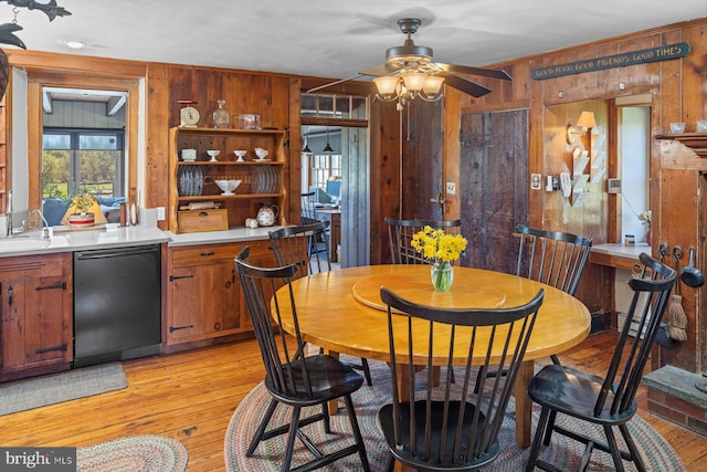 dining space featuring light hardwood / wood-style flooring, wooden walls, and ceiling fan