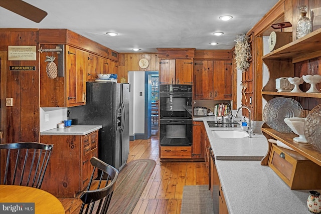 kitchen with sink, black appliances, and light hardwood / wood-style floors