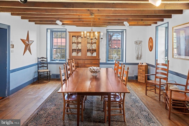 dining area featuring a wealth of natural light, beam ceiling, and dark wood-type flooring