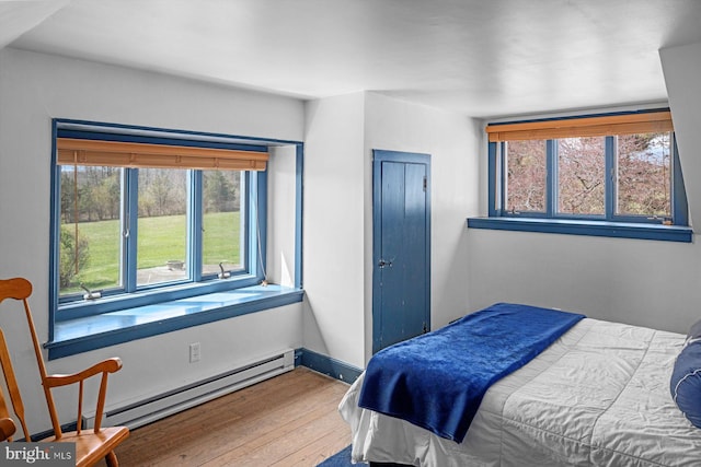 bedroom featuring a baseboard radiator, multiple windows, and hardwood / wood-style floors