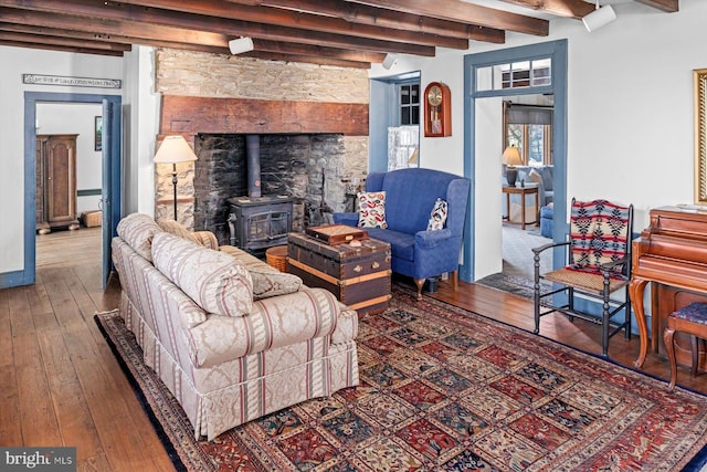 living room with beamed ceiling, hardwood / wood-style floors, and a wood stove