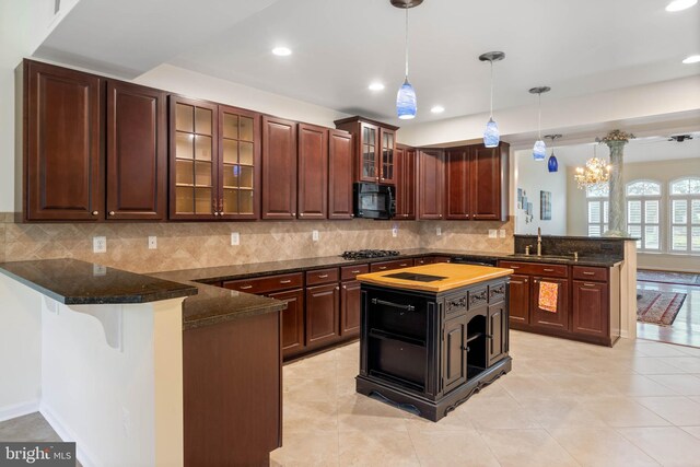 kitchen with hanging light fixtures, kitchen peninsula, decorative backsplash, and dark brown cabinets