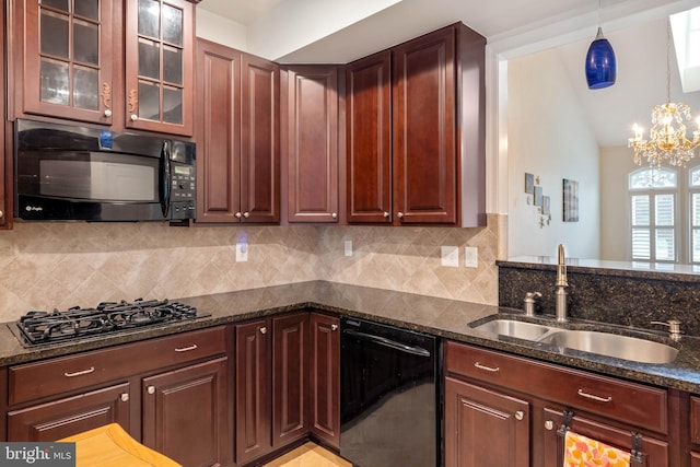 kitchen featuring pendant lighting, a chandelier, sink, black appliances, and dark stone countertops