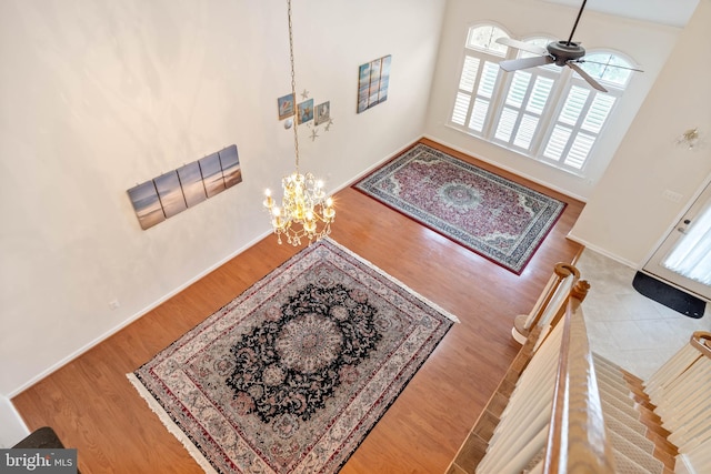 entrance foyer with ceiling fan with notable chandelier, a towering ceiling, and light hardwood / wood-style flooring