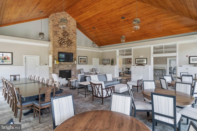 dining room featuring wooden ceiling, a stone fireplace, and high vaulted ceiling