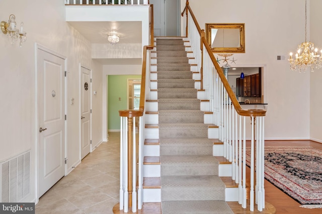 staircase with a notable chandelier and tile patterned floors