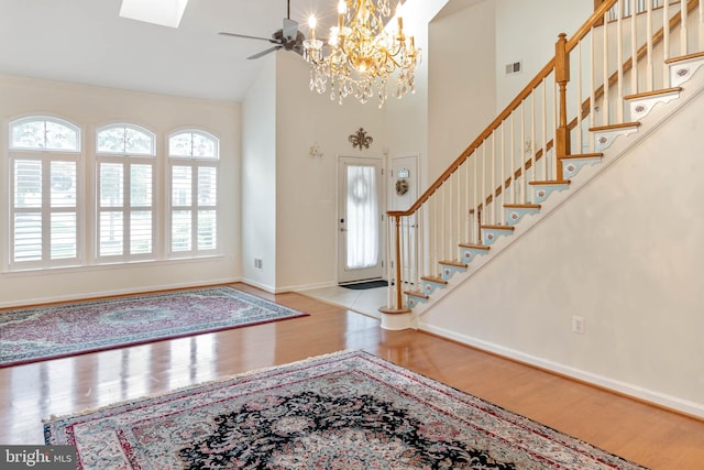 entryway featuring light wood-type flooring, ceiling fan with notable chandelier, and high vaulted ceiling